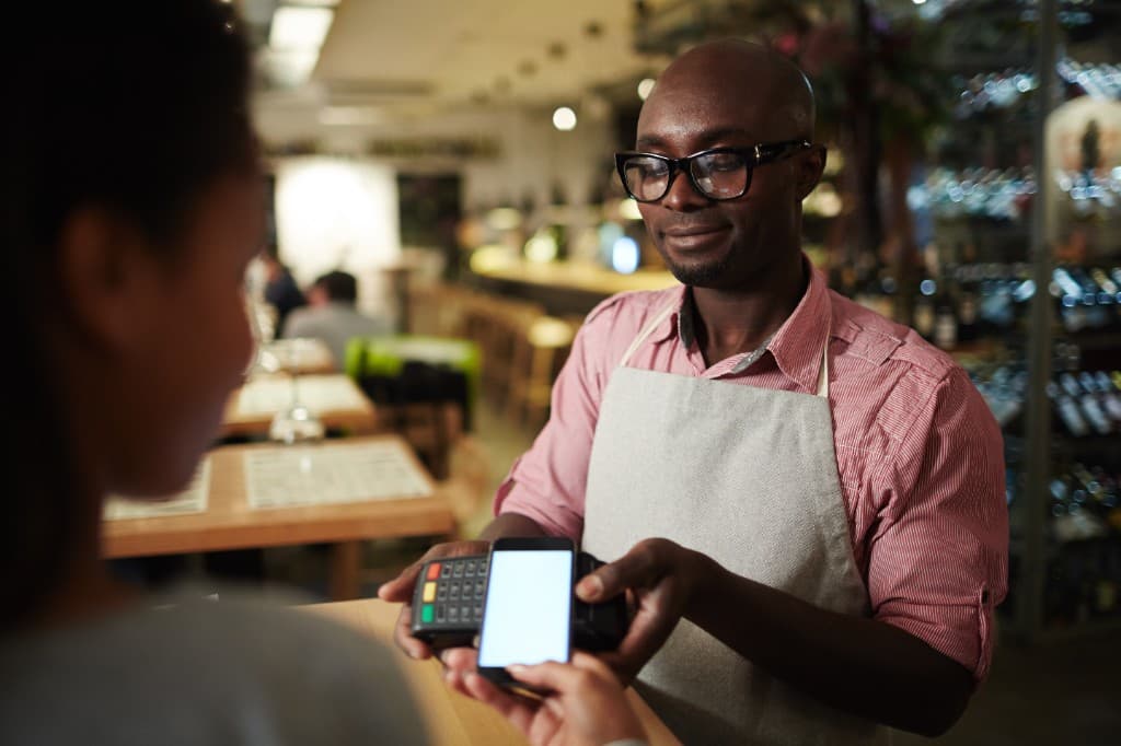 Serveur encaissant un client par paiement mobile sur TPE en restaurant