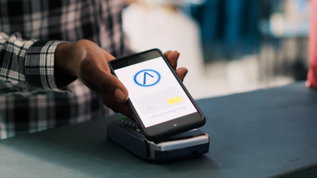 Smartphone affichant une confirmation de paiement au-dessus d'un TPE